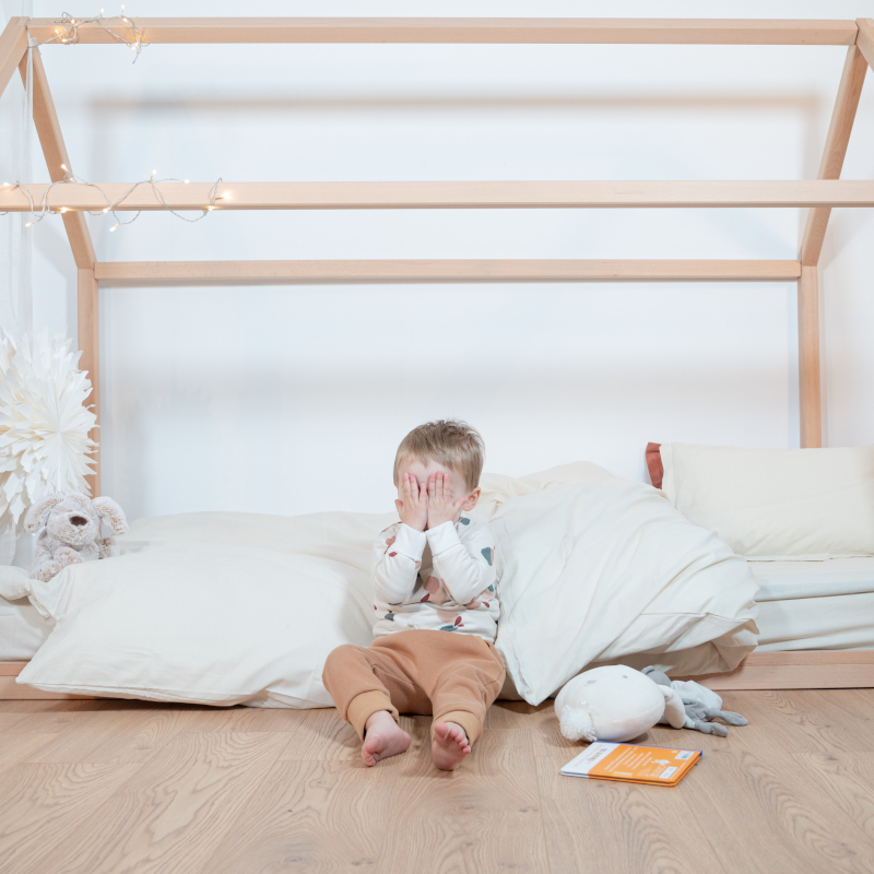 Image représentant un enfant jouant devant le lit cabane Cosme