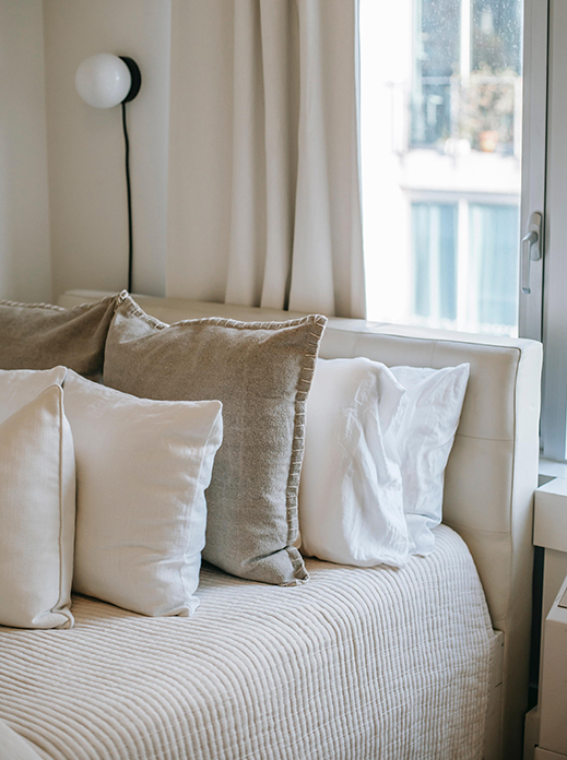 Coussins sur un matelas en latex naturel dans une chambre cocooning beige et blanche 