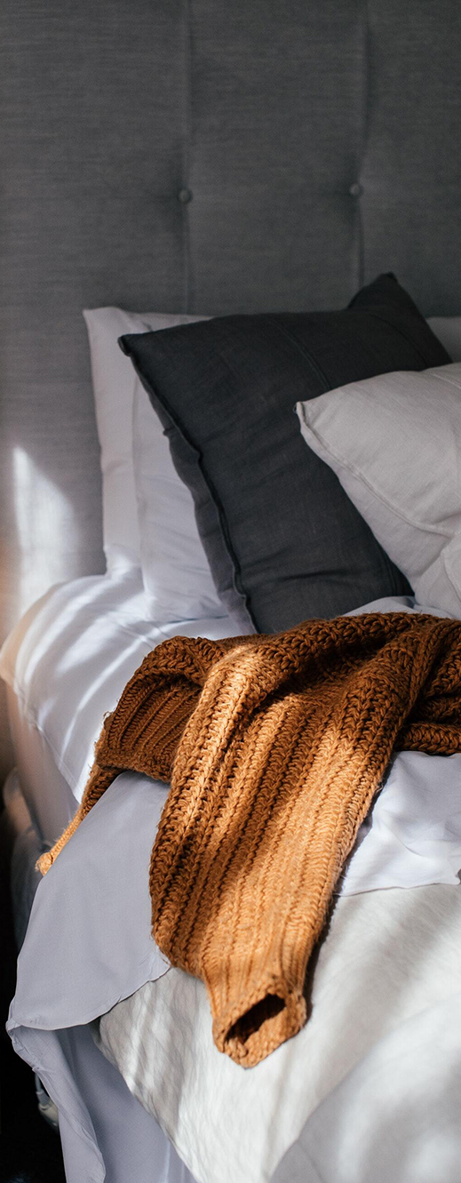 Oreillers et plaid orange sur un matelas français haut de gamme avec une tête de lit gris