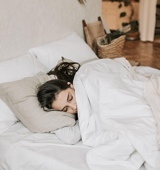 Femme allongée sur un matelas dense en latex naturel dans une chambre beige et blanche