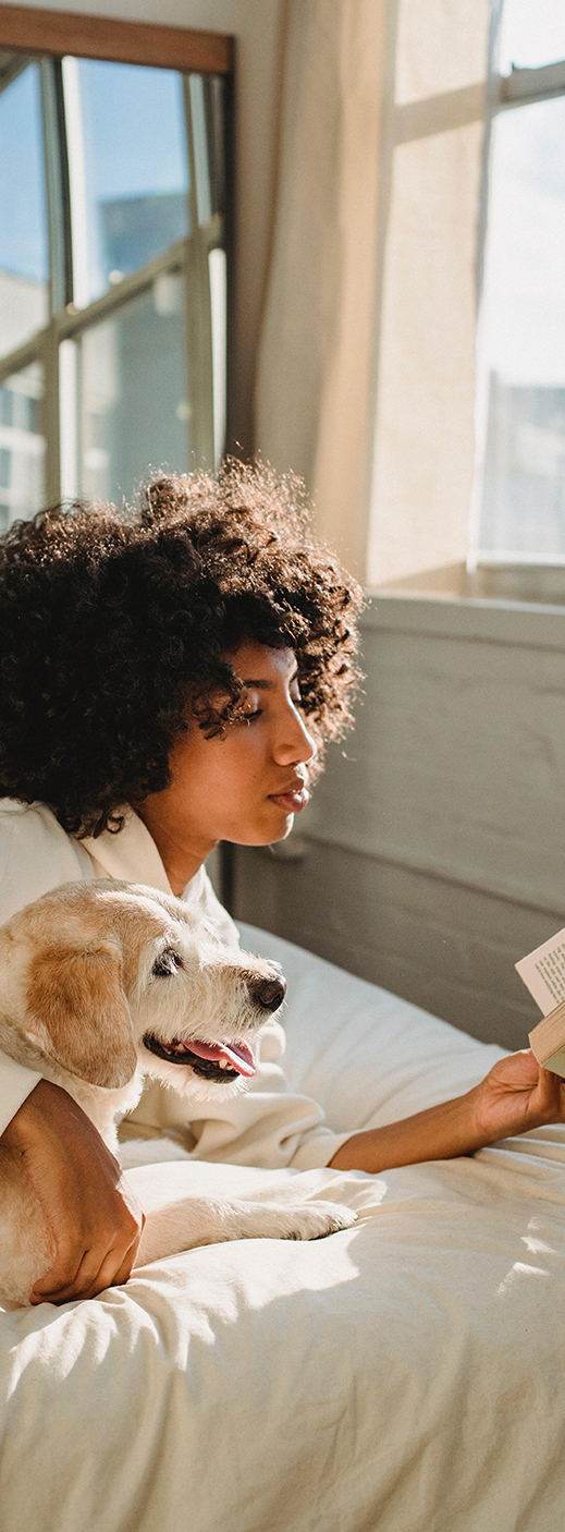 Femme allongée avec un chien lisant un livre sur un matelas en latex naturel