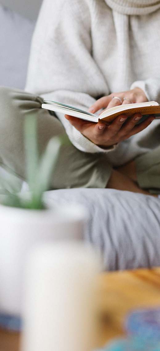 Femme qui lit un livre sur son matelas en latex naturel entourée de plantes vertes