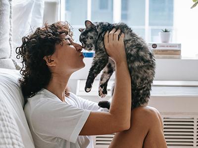 Femme assise contre son matelas en latex naturel faisant un calin à son chat