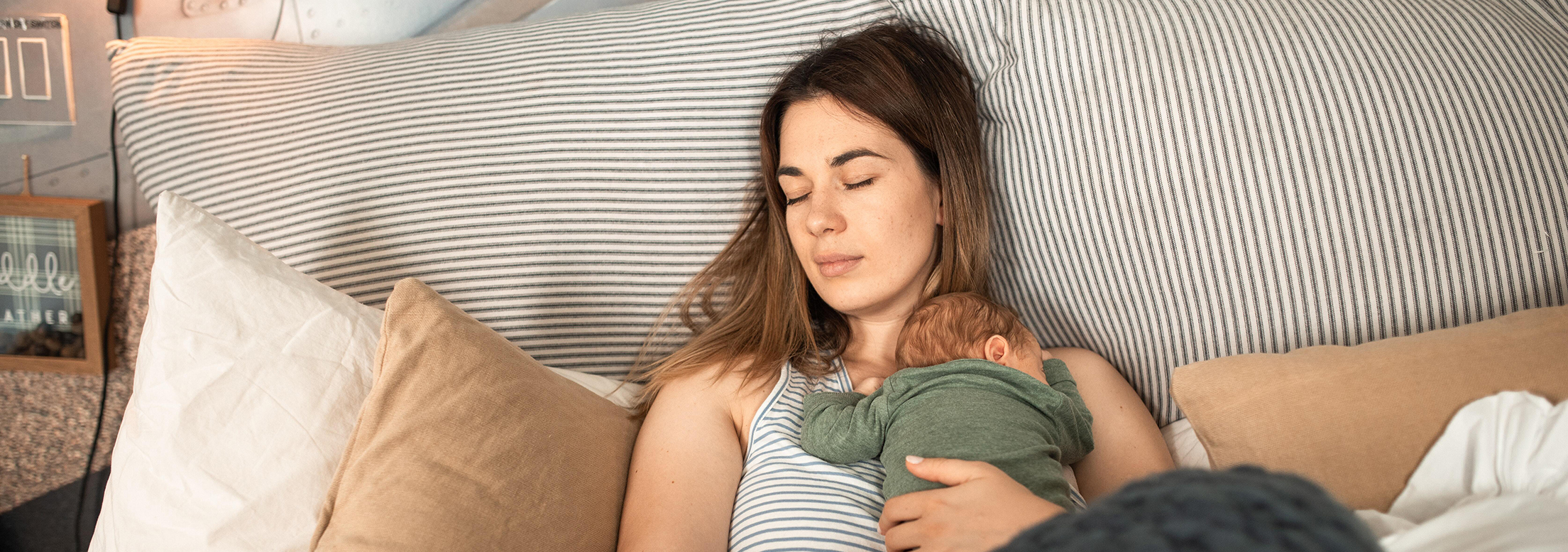 Femme allongée tenant un bébé contre elle