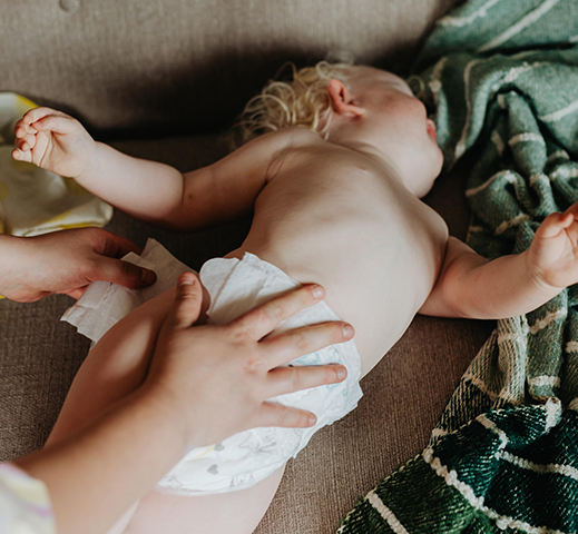 Femme qui change la couche d’un bébé sur un canapé