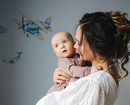 Maman dans une chambre bébé avec son petit dans les bras