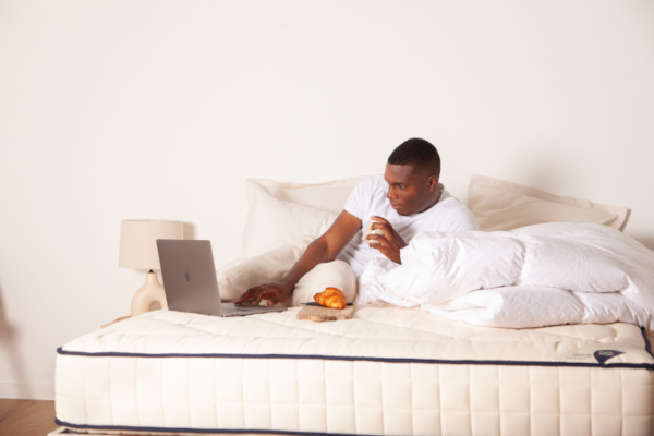 Photo représentant un homme sur un matelas regardant son ordinateur