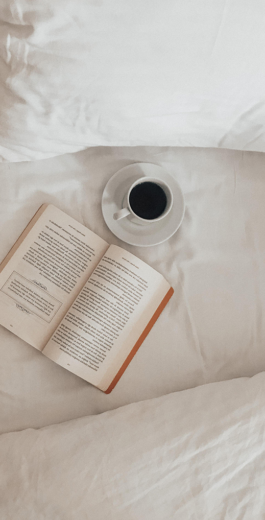Livre ouvert et tasse de café posés sur un matelas dense en latex naturel