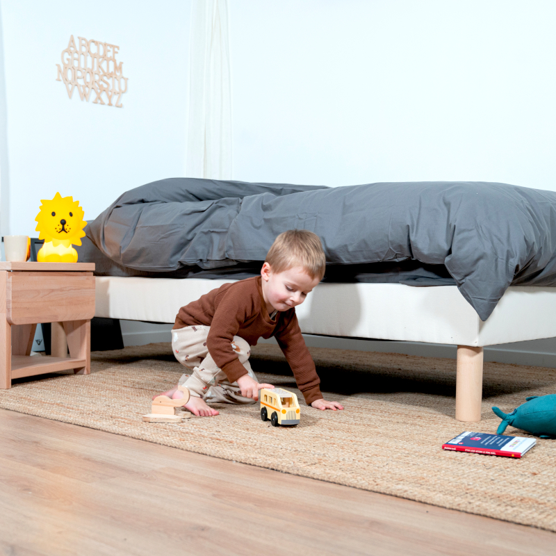 image représentant un enfant jouant à côté d'un lit