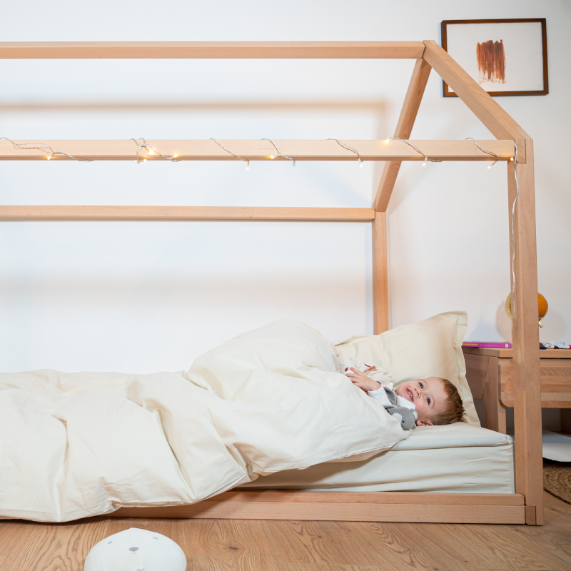 Image représentant un enfant se reposant dans un lit cabane avec la parure blanc cassé