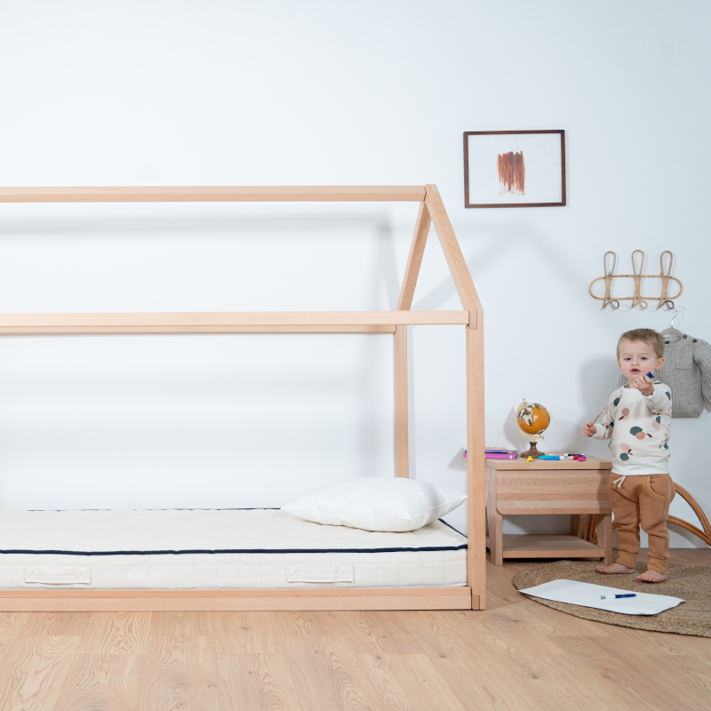 Image représentant un enfant jouant à côté du lit cabane Cosme