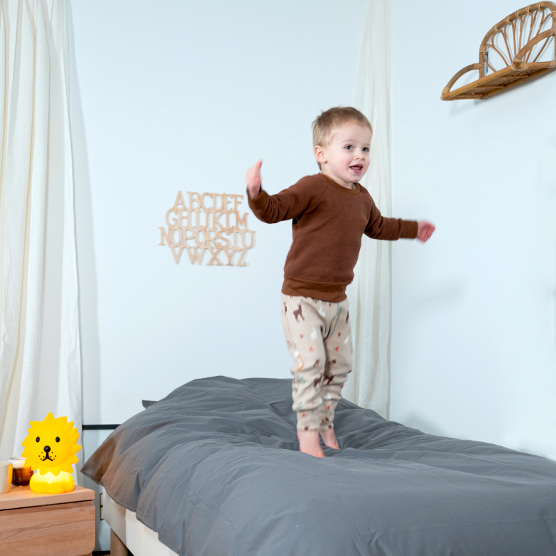 image représentant un enfant sautant sur un lit composé d'une parure de lit en coton bio gris