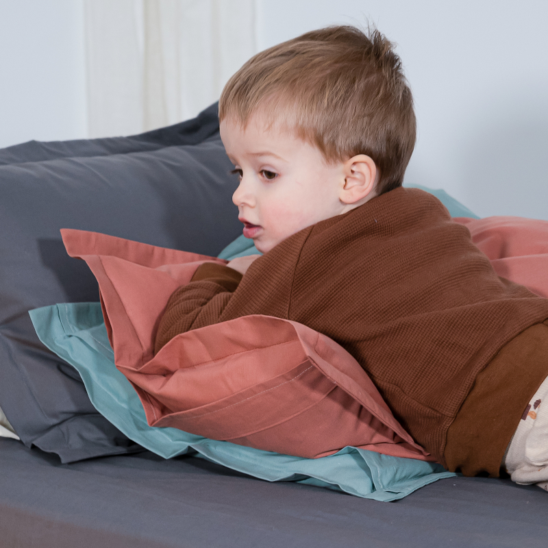 image représentant un enfant allongé sur des oreillers Cosme