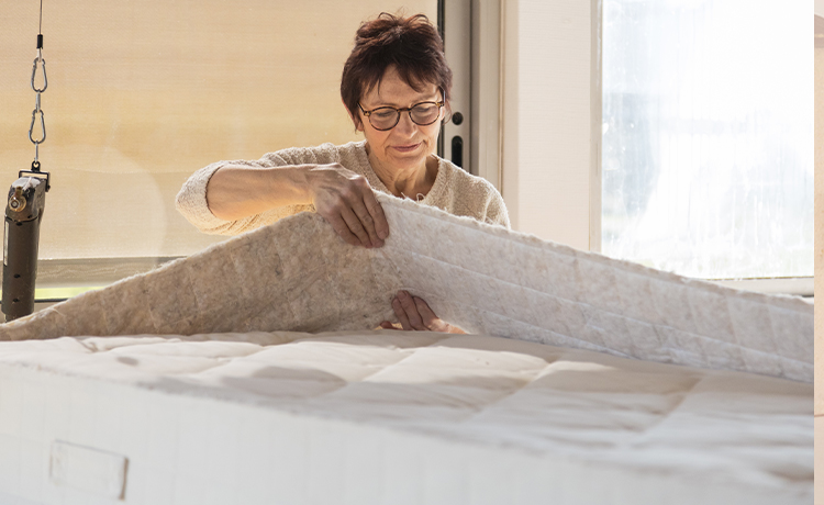 Artisan travaillant sur un matelas dans l'atelier Cosme Literie en France