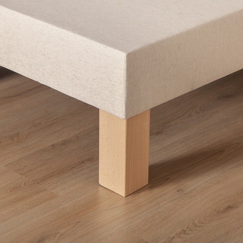 Gros plan sur les pieds en bois d'un sommier tapissier Cosme.