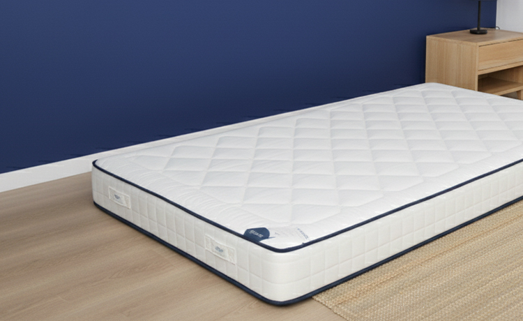 Matelas posé au sol à côté d'un sommier vide pour tester l'origine de l'inconfort.