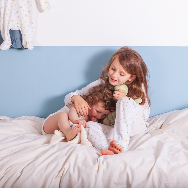 Image représentant deux enfants jouant dans un lit Le Petit Cosme